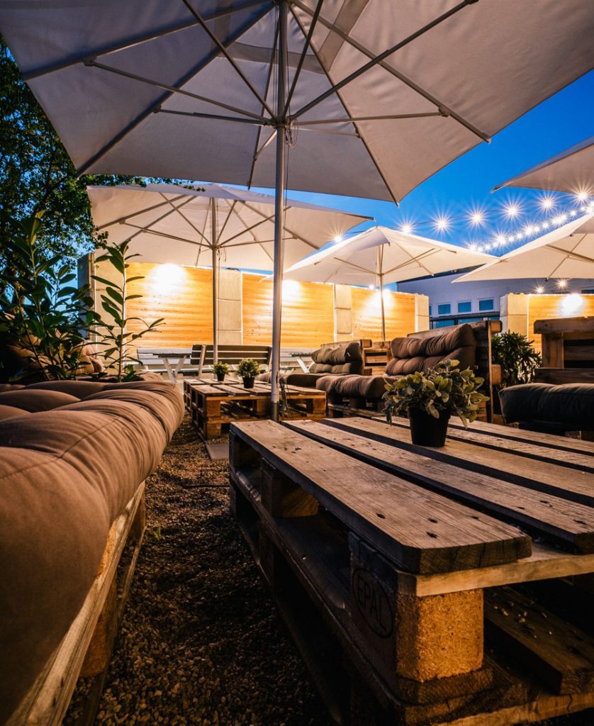Sommergarten am Schiff am Abend - rustikale Palettenmöbel, atmosphärische Beleuchtung.
